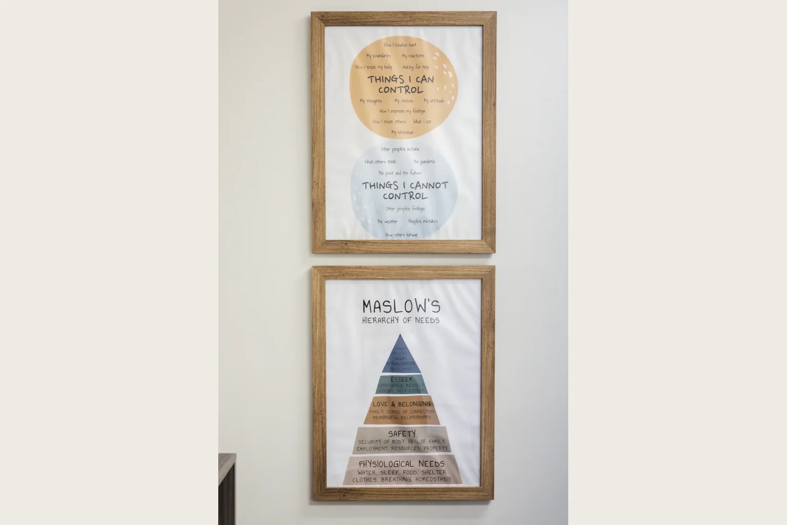 Two wooden-framed posters on a pale wall.
