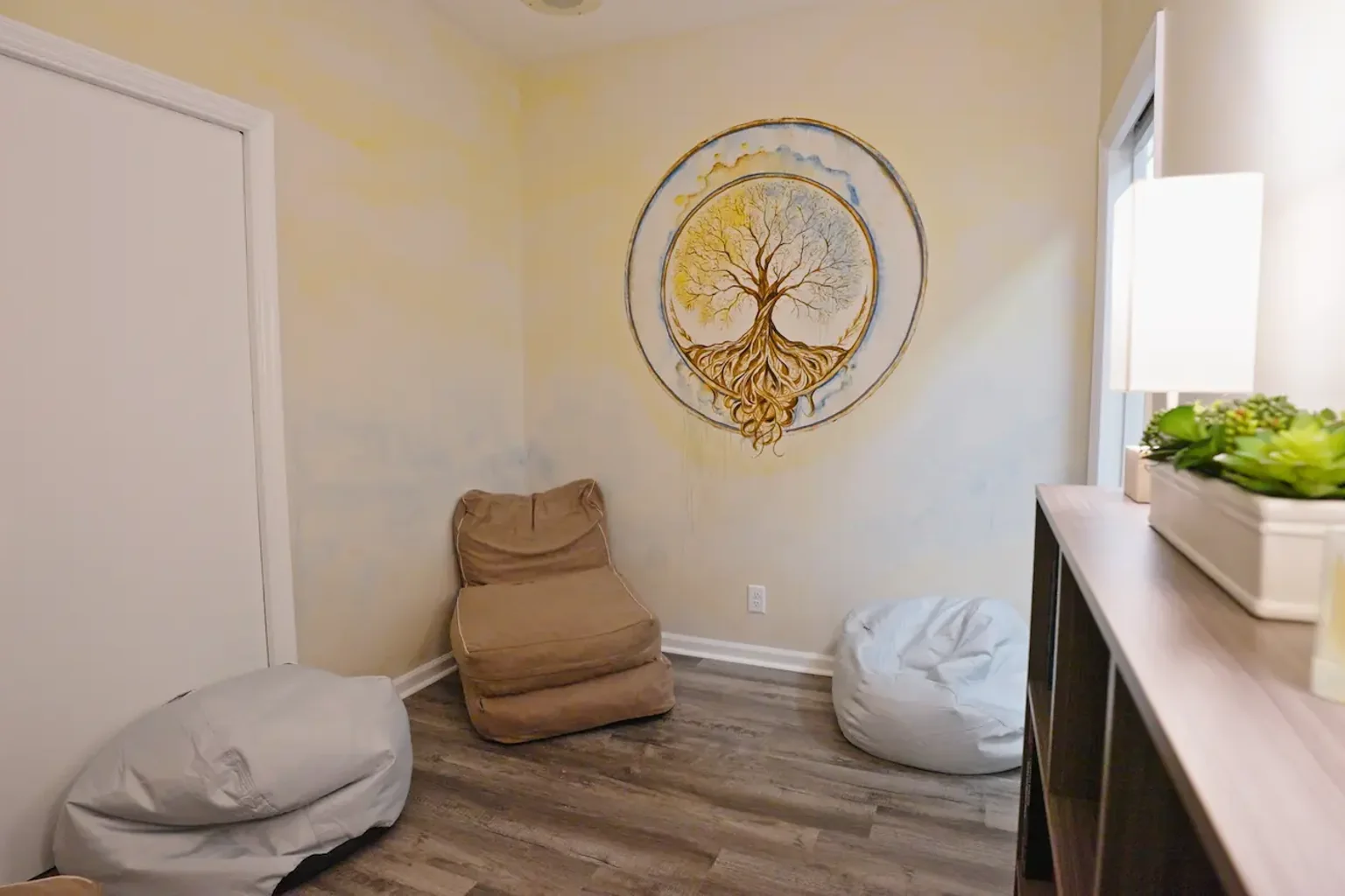 Quiet room with three floor cushions, a tree mural and a window.