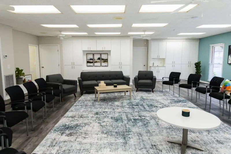 Group room at River City Recovery with a tree mural and brown chairs